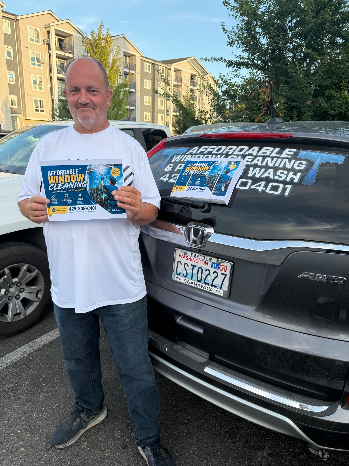 MailDude customer holding a printed marketing flyer beside his branded work vehicle